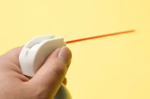 A hand holding a can of spray lubricant with its red applicator straw extended